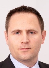A person wearing a suit and tie smiling at the camera
Description automatically generated